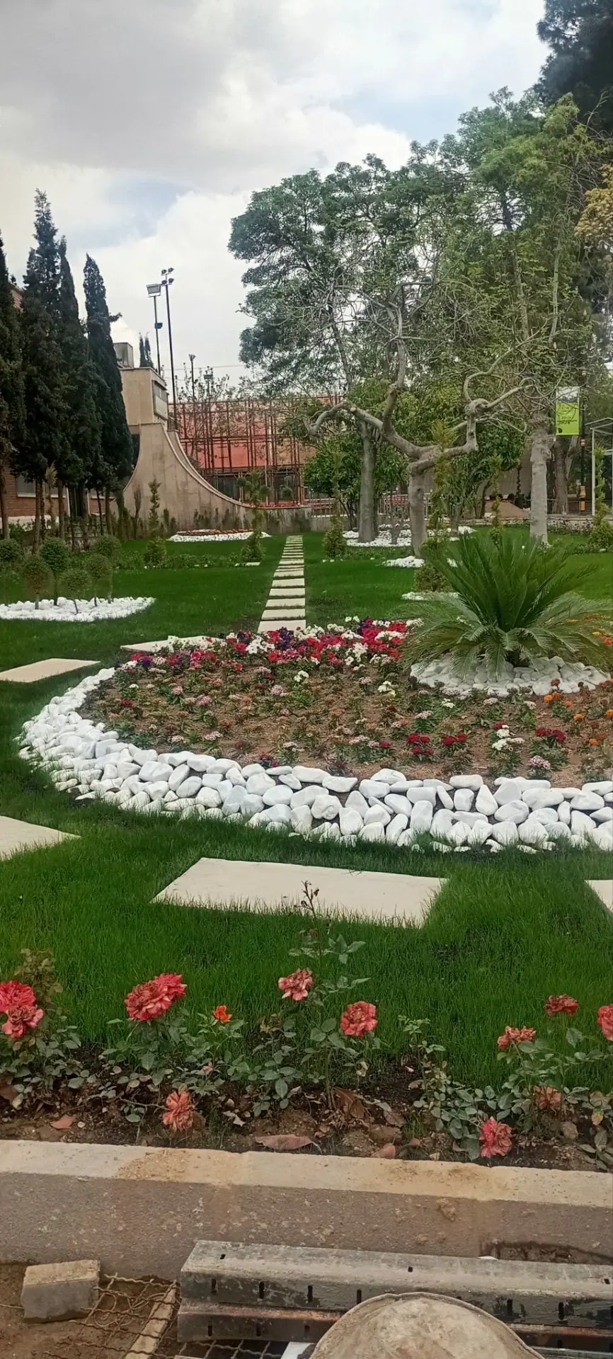 باغچهٔ گل حاشیه‌دار با سنگ سفید و گیاه نخل زینتی کنار چمن